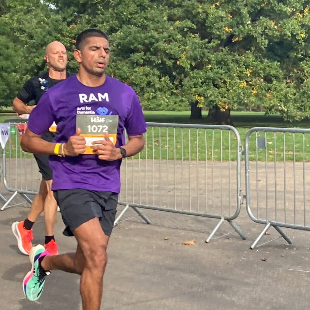 A single runner wearing an Arts for Dementia purple t-shirt running with a concerntrated expression on their face