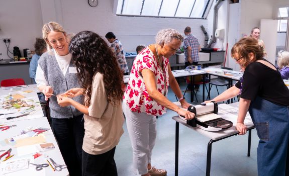 Participants using the press machine and discussing embossing materials