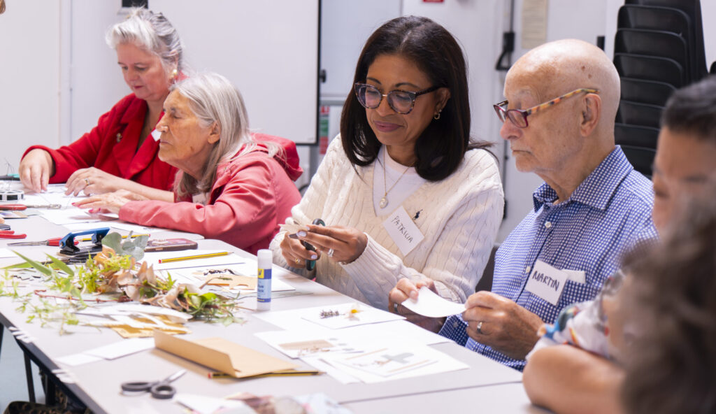 Participants working at a a table covered with flowers to create embossed designs