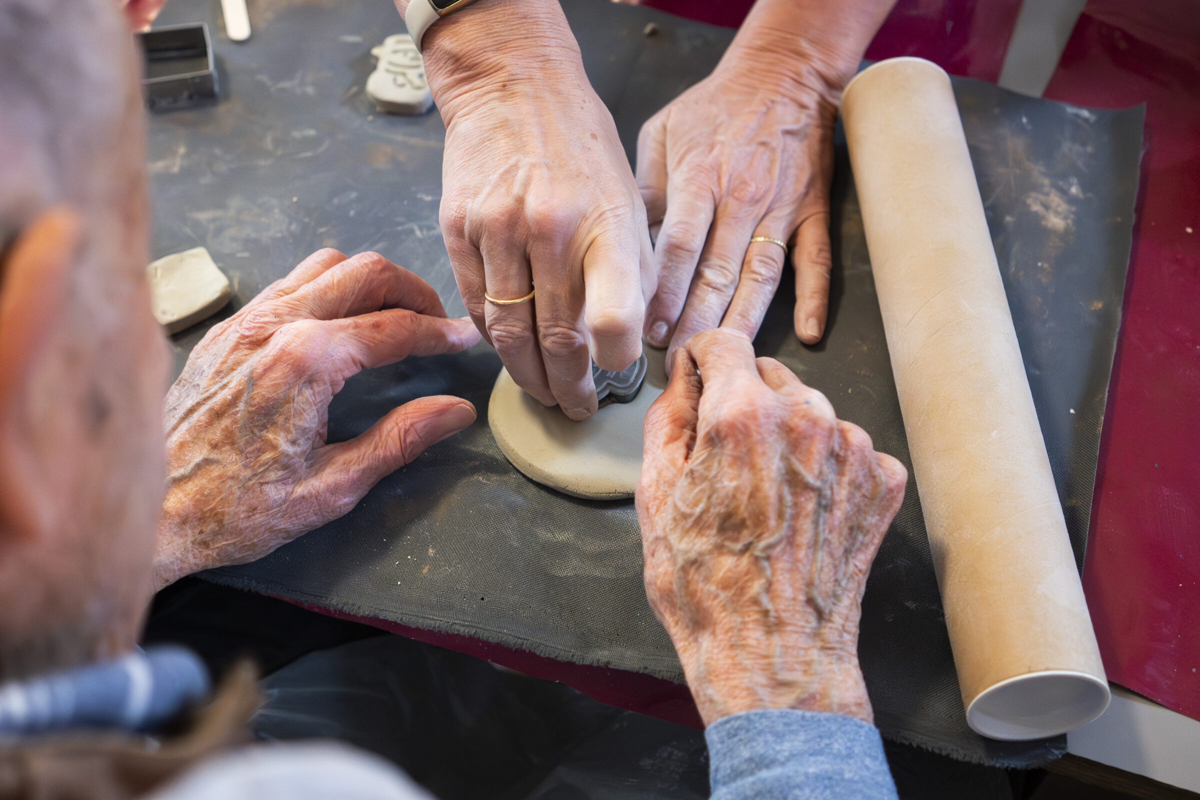 Artist and participants hands working on clay together