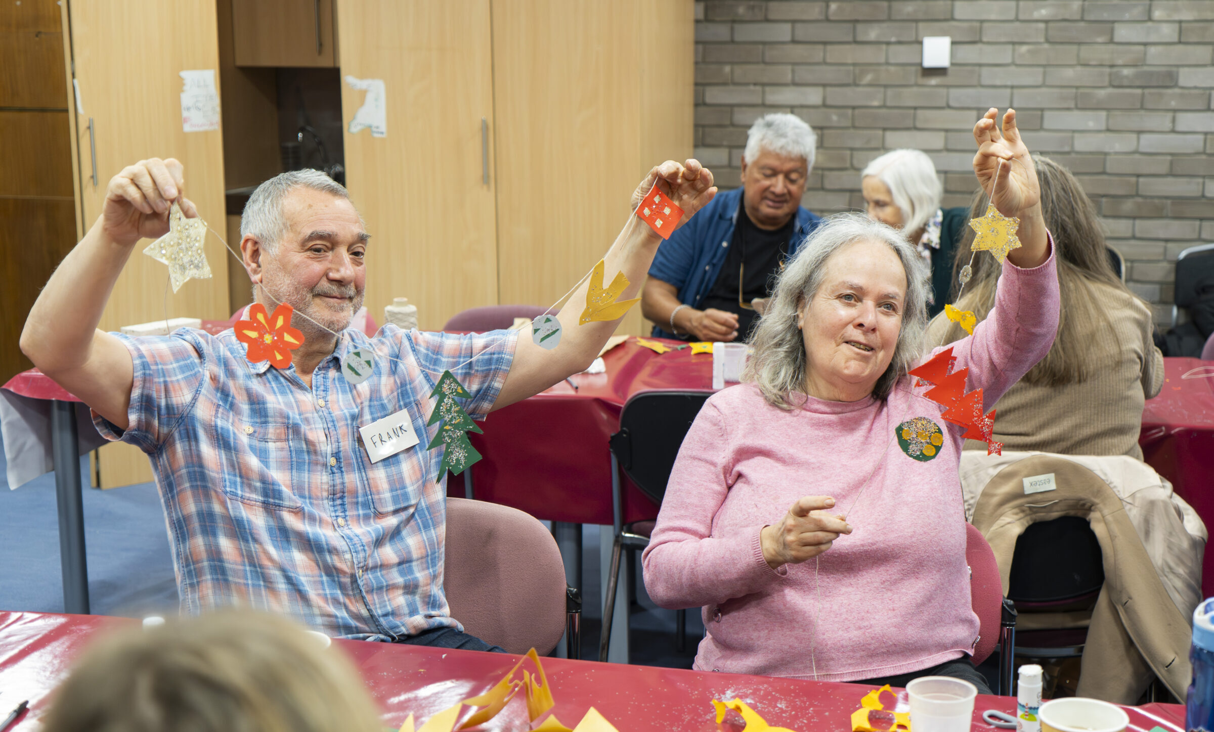 Frank and Bee holding up bunting they have made during a 3D art workshop